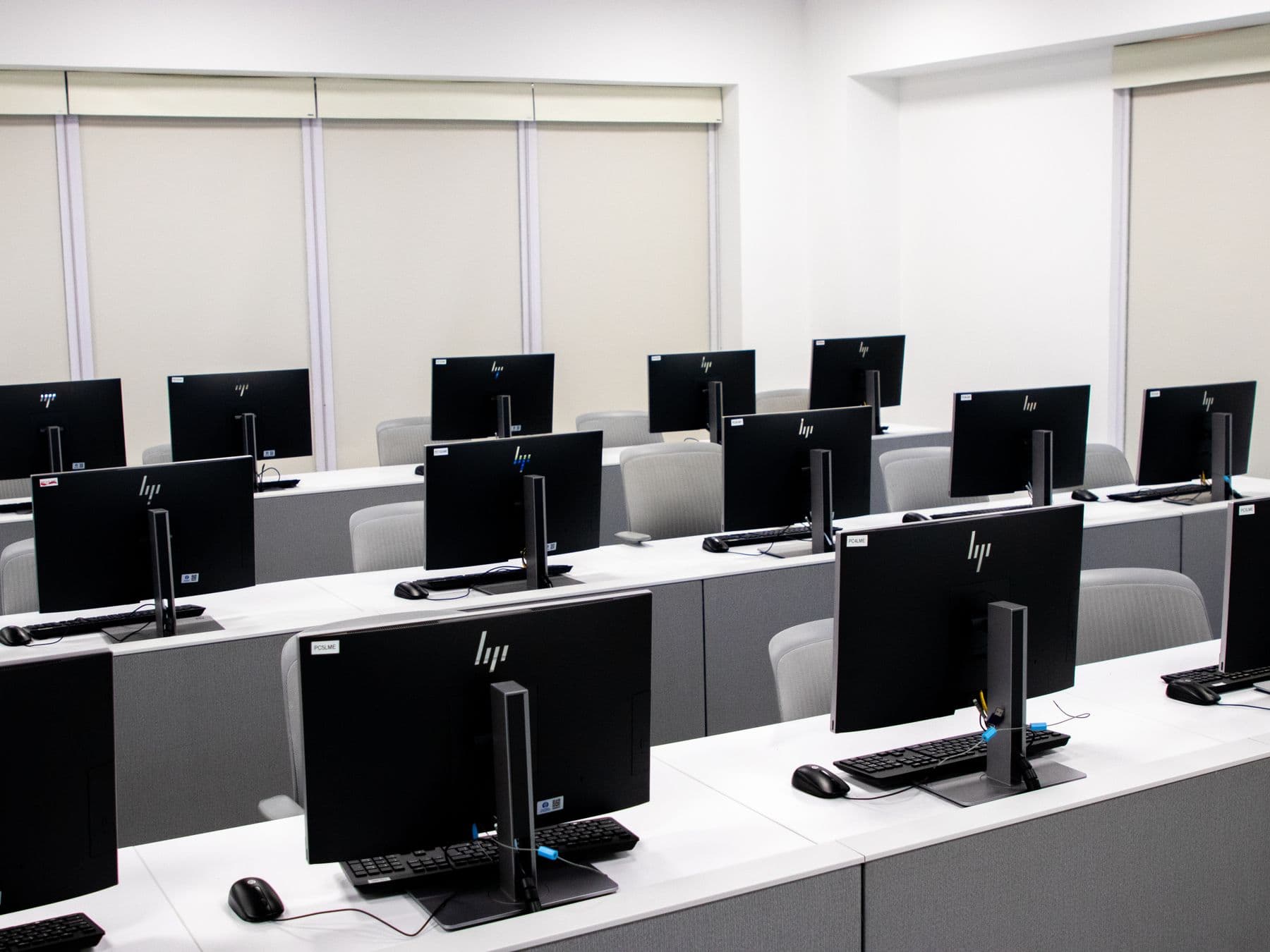 Rows of identical monitors on white desks across an open-plan floor