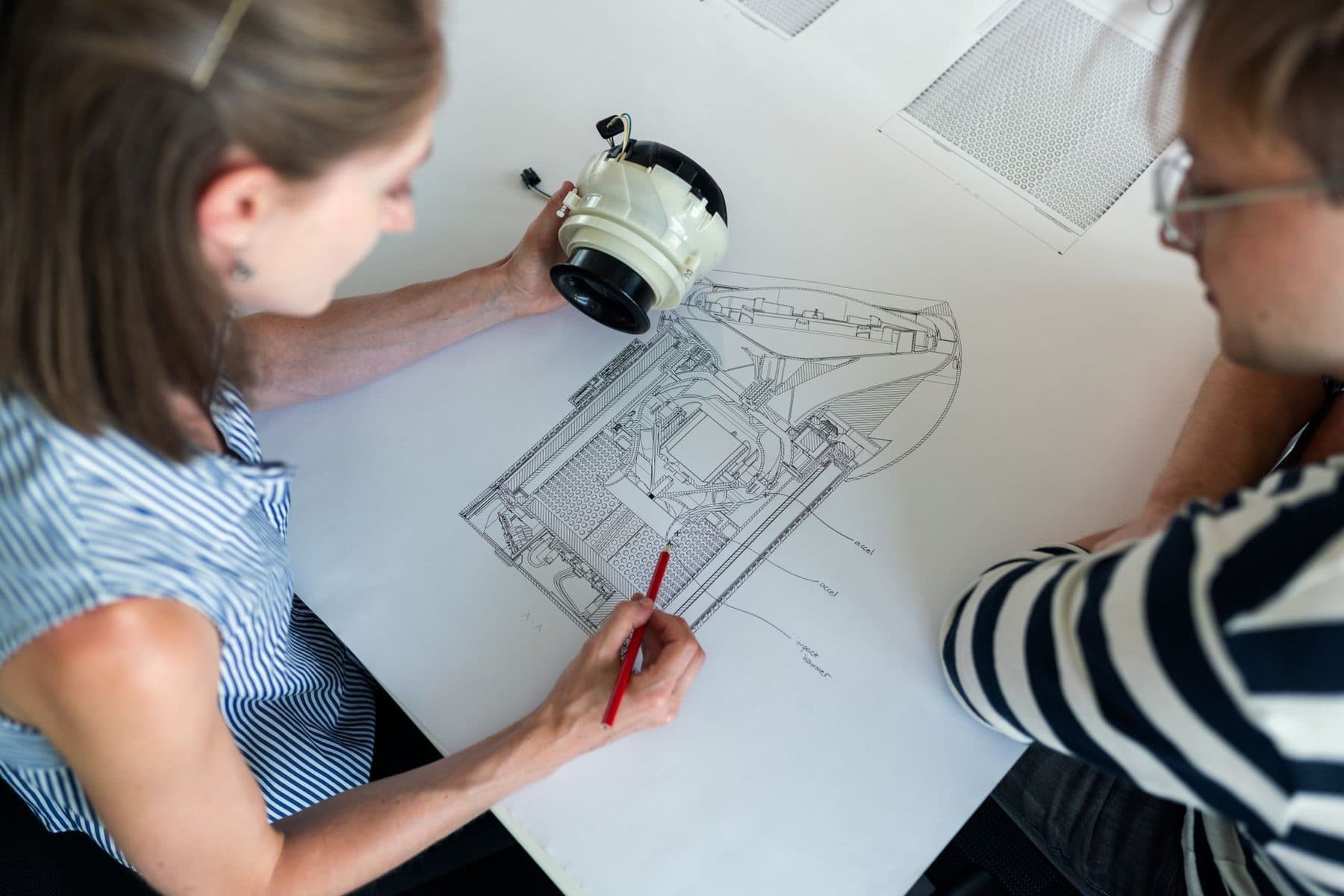 Two engineers working over a technical drawing